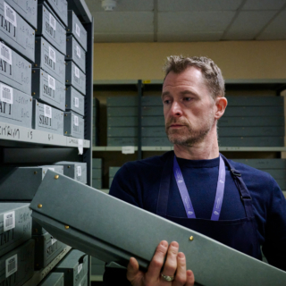 A conservator returning a box to a storage shelf.