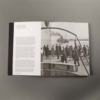 An open book spread revealing two pages. On the right side is a black and white photo of a steamboat departing from Dún Laoghaire.