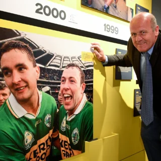 Exhibition timeline on the year 2000. It features a closeup of two Kerry players celebrating. Jacko poses for a photo in front of the panel.