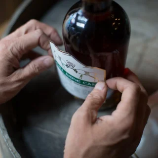 Closeup of a person fixing a label to a bottle.