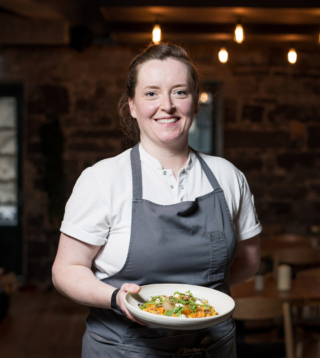 Portrait of a chef holding a plate of food.