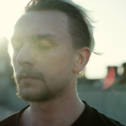 A man with his eyes closed contemplates, the sun is setting in the background