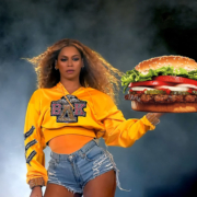Beyonce holding a giant Whopper burger from burger king, she is back lit and there is dry ice in the air