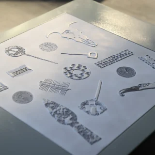 Close-up of graphic relief panel depicting historical artefacts like brooches and spear heads