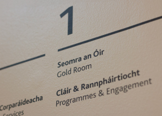 Close-up detail of white vinyl lettering applied to a dark wall surface showing the signage typography