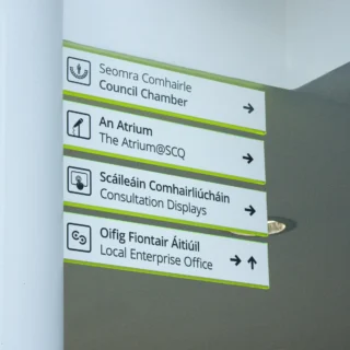 Wall-mounted directional signs in English and Irish with icons, pointing to the Council Chamber, The Atrium, Consultation Displays, and the Local Enterprise Office.