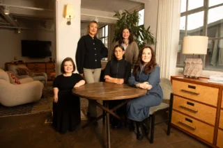 Tilting the Lens team members, Sinéad, Áine, Laia, Emma and Orla gather around a table facing the camera together.