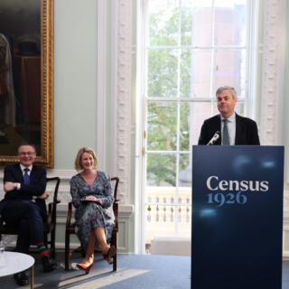 Ambassador Martin Fraser speaks at a podium branded “Census 1926” during an indoor launch event, with Minister O’Donovan and Director of the Archives Orlaith McBride seated.